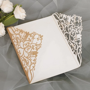 Détail macro du faire-part de mariage découpé au laser avec paillettes dorées et fleurs