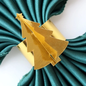 Détail macro du rond de serviette sapin de Noël doré sur satin vert foncé