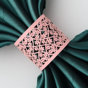 Detail of pink laser-cut paper napkin ring with intricate floral lace and heart pattern