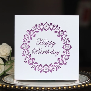 Macro detail of laser-cut floral pattern and Happy Birthday text on purple greeting card
