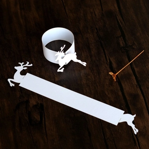 Macro view of white paper reindeer napkin rings in flat and folded holiday table states