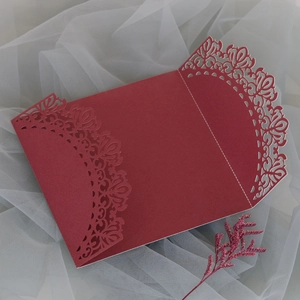 Detalle de patrón floral cortado con láser en invitación de boda roja con fondo gasa