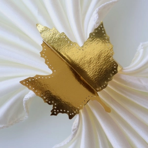 Detailed close-up of golden maple leaf napkin ring with hammered texture and laser-cut dots