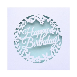 Detail of laser-cut white paper birthday card featuring ornate floral lace and Happy Birthday text