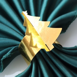 Gros plan d'un rond de serviette sapin de Noël doré brillant sur satin vert foncé
