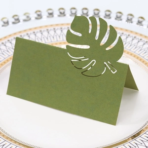 Vue rapprochée d'un marque-place vert avec découpe de feuille de monstera sur une assiette