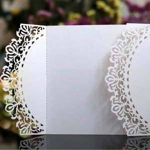 Elegant white laser-cut wedding invitation card with intricate floral lace on pearl paper