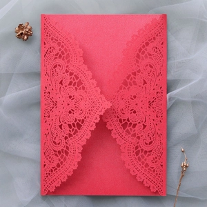 Close-up of red laser-cut wedding invitation cover with elegant hollow lace pattern