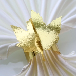 Close-up of golden maple leaf paper napkin ring with textured metallic finish