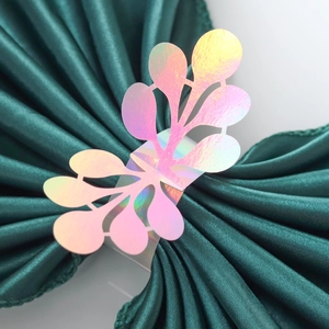 Detail of laser-cut iridescent napkin ring with hollow leaf pattern on green satin