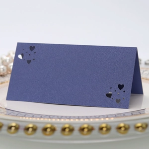 Detalle de la tarjeta de mesa azul marino con corazón cortado por láser en plato elegante