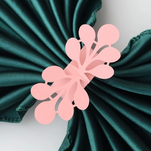 Close-up of pink laser-cut pearl paper napkin ring with floral leaf pattern detail