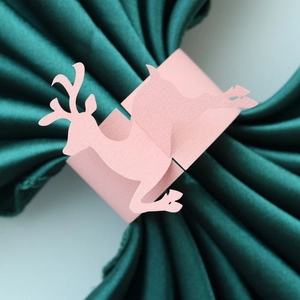 Pink reindeer paper napkin ring detail on dark green satin fabric for Christmas decor
