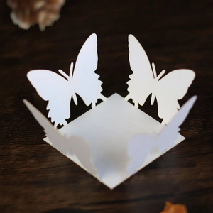 Detailed laser-cut white butterfly paper favor box with pearlized finish on wood texture