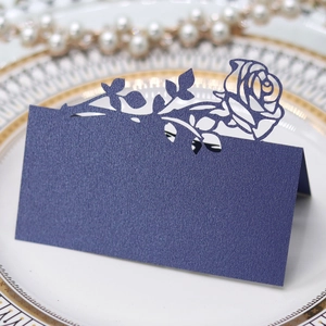 Close-up of laser-cut rose place card in pearlescent navy blue on a luxury dinner plate