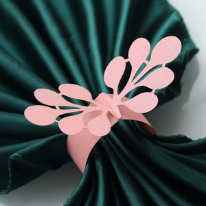 Close-up of laser-cut pearlescent pink paper napkin ring with elegant leaf patterns