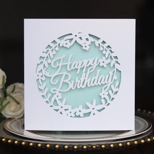 Detail of laser-cut Happy Birthday card with floral patterns on elegant porcelain plate