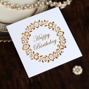 Macro detail of square white birthday card with gold foil wreath and Happy Birthday text