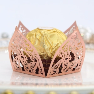 Macro detail of laser-cut rose gold butterfly favor box with metallic pearl finish