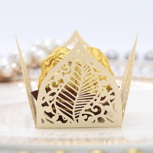 Macro shot of laser-cut leaf pattern pearl paper cupcake wrapper for wedding decor