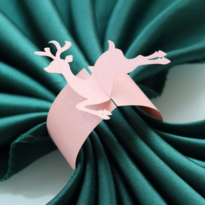 Macro view of pink reindeer paper napkin ring on dark green silk background fabric