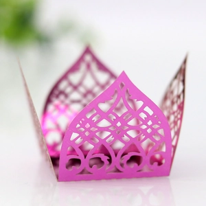 Detail of laser-cut pink paper cupcake wrapper with intricate gothic hollow patterns