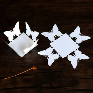 Detail of white pearlescent paper butterfly candy box with laser cut hollow patterns