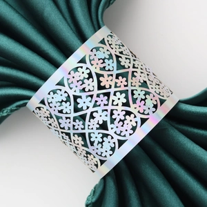Detail of laser-cut floral napkin ring with holographic finish on green satin fabric