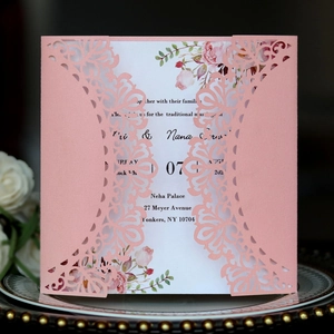 Detalle de invitación de boda rosa cortada con láser e inserto floral sobre plato
