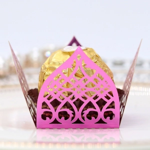 Macro detail of laser-cut pink paper cupcake liner with intricate floral hollow pattern