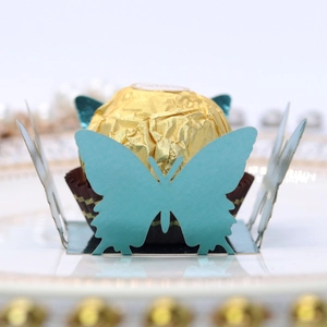 Macro shot of laser-cut teal butterfly paper candy holder for wedding chocolate decoration