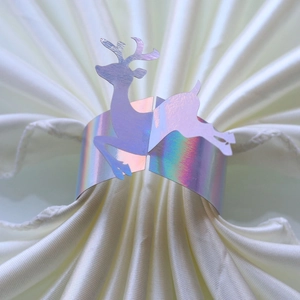 Close-up of holographic laser-cut reindeer napkin ring on a white silk napkin
