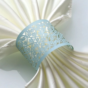 Close-up of laser-cut pearlescent light blue napkin ring with fine floral pattern
