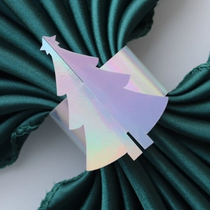 Détail d'un rond de serviette sapin de Noël irisé sur un tissu plissé vert foncé