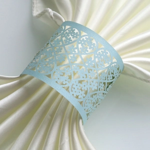 Close-up of light blue laser-cut floral paper napkin ring with elegant lace texture