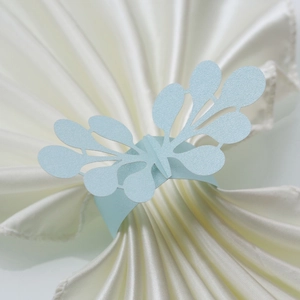 Close-up of light blue laser-cut paper napkin ring with elegant floral lace leaf pattern