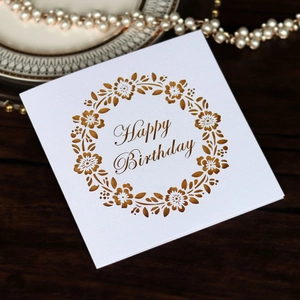 Elegant laser-cut Happy Birthday card with floral wreath design on dark wood background