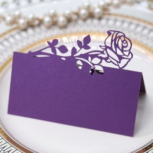 Detail of laser-cut purple rose paper place card with pearlescent finish on a plate