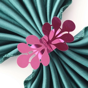 Detail of rose red leaf napkin ring on dark green satin fabric for wedding table decor