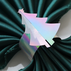 Gros plan du rond de serviette sapin de noël iridescent sur un tissu en satin vert