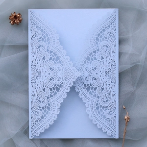 Macro detail of laser-cut light blue lace wedding invitation with pearl texture