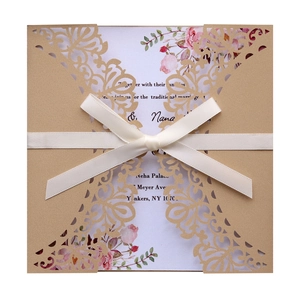 Detail of laser cut wedding invitation with floral inner card and cream ribbon bow