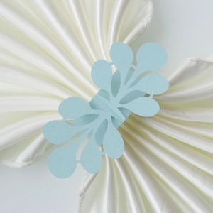 Detail of light blue laser-cut napkin ring with intricate lace pattern for weddings