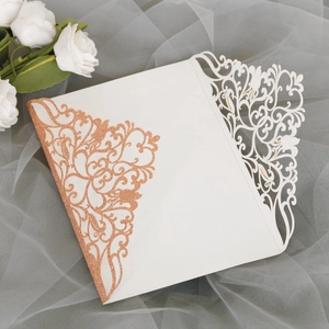Détail de l'invitation de mariage découpée au laser avec dentelle fleurie rose doré