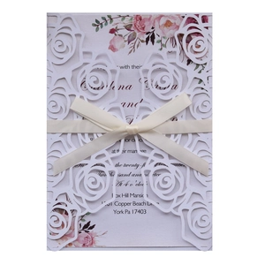 Elegant laser-cut wedding invitation featuring white rose hollow design and cream satin ribbon