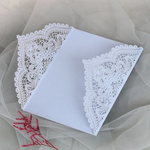 Makroansicht der weißen lasergeschnittenen Hochzeitseinladung mit floralen Spitzendetails