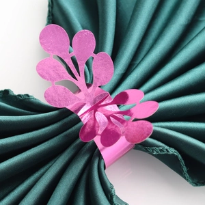 Macro shot of a pink butterfly napkin ring with hollow patterns on green satin fabric