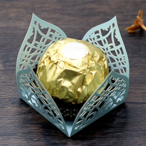 Macro detail of laser-cut paper wedding favor box with intricate hollow lace pattern