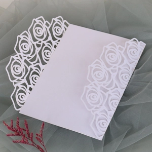 Detailed laser-cut rose patterns on white wedding invitation covers with floral cutouts
