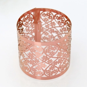 Close-up of rose gold laser-cut napkin ring featuring intricate floral and heart patterns